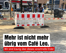 Ein Foto einer Baustelle auf dem Leopoldplatz. Es ist nur eine Absperrung zu sehen, dem Café wurde komplett abgerissen. Darunter steht in einer Textbox „Mehr ist nicht mehr übrig vom Café Leo. Wir sind traurig über dieses vorschnelle Ende!“