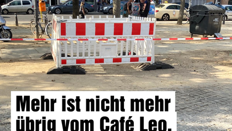 Ein Foto einer Baustelle auf dem Leopoldplatz. Es ist nur eine Absperrung zu sehen, dem Café wurde komplett abgerissen. Darunter steht in einer Textbox „Mehr ist nicht mehr übrig vom Café Leo. Wir sind traurig über dieses vorschnelle Ende!“