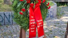 Foto des Kranzes der Linken in der Bezirksverordnetenversammlung Berlin Mitte in Gedenken an die Opfer der Berliner Mauer. Rote Rosen in einem grünen Kranz. Auf der linken Schleife steht „Wir gedenken den Opfern an der Berliner Mauer“. 