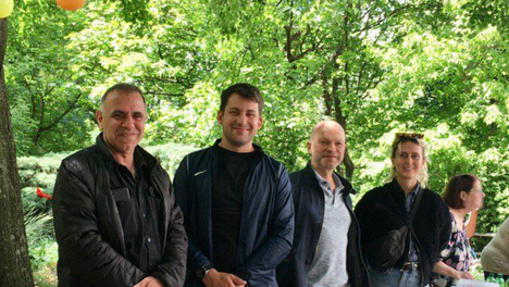 stand kindertag Gruppenfoto von der Standbetreuung beim Sommer- und Kinderfest im Jugendpark der WBM. Der Tisch ist mit leckerem selbst gemachten Kuchen bedeckt. Zu sehen sind die Bezirksverordneten Thilo Urchs, Leonard Diederich, Sven Diedrich und unsere Fraktionsmitarbeitende Rosa Schick. Im Hintergrund ist es sehr grün, alle Bäume und Sträucher tragen Blätter. Oben Links ist das Logo der Fraktion DIE LINKE. In der BVV Berlin-Mitte eingefügt.