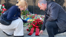 Foto: Die Bezirksverordneten Martha Kleedörfer und Thilo Urchs legen einen Blumenkranz aus roten Rosen und anderen roten Blüten beim Sowjetischen Ehrenmal im Tiergarten nieder.