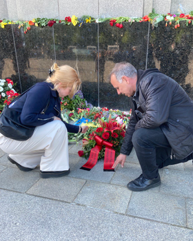 Foto: Die Bezirksverordneten Martha Kleedörfer und Thilo Urchs legen einen Blumenkranz aus roten Rosen und anderen roten Blüten beim  Sowjetischen Ehrenmal im Tiergarten nieder.