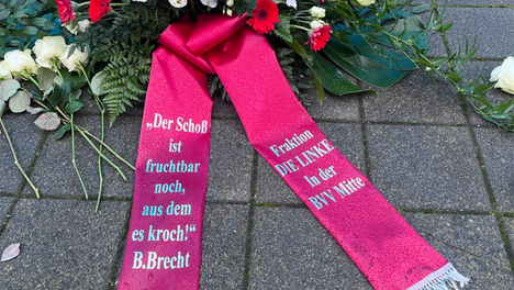 Foto des Gedenkkranzes der Fraktion DIE LINKE. in der BVV Mitte vor dem Mahnmal für die Euthanasieopfer der „T4-Aktion“. Rote und Weiße Blumen, auf einer Schärpe am Kranz steht „Der Schoß ist fruchtbar noch, aus dem es kroch!“ - B. Brecht