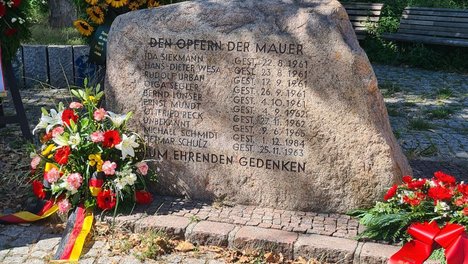 Foto des Gedenksteins für die Maueropfer in der Bernauer Straße umgeben von mehreren Gedenkkränzen.