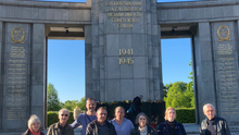 Gruppenfoto: Eine Gruppe Menschen steht in Andacht vor dem Sowjetischen Ehrenmal im Tiergarten.