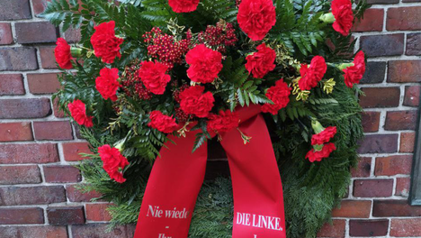 Blumenkranz mit roten Blüten der Fraktion DIE LINKE. in der BVV Berlin-Mitte. Auf den Bändern steht der Name der Fraktion und: „Nie wieder – Ihr Schutz ist unsere Pflicht“. 