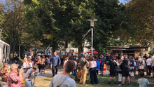 Foto vom Sommerfriedensfests. Dutzende Menschen sind im Sonnenschein auf die verschiedenen Attraktionen verteilt.